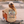 A person sitting on a skateboard at a concrete skatepark, viewed from behind, wearing a beige graphic t-shirt with a retro van illustration and the text 'HOME IS WHERE YOU PARK IT' and 'THE VAN LIFE SOCIETY'.