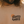 Close-up of a person wearing a beige crewneck t-shirt with a graphic print that reads 'STOKED & WOKE CLOTHING' in black text next to an orange circle, with the person's beard and hair visible.